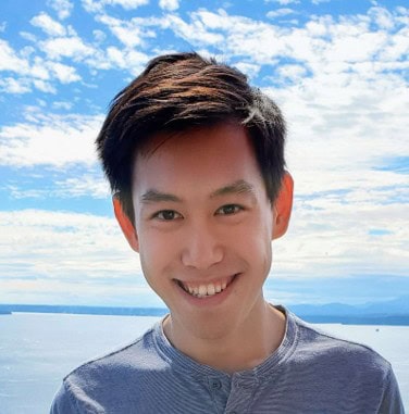 Jossou Research Group Member Portrait Young researcher smiling outdoors with sky and water background.